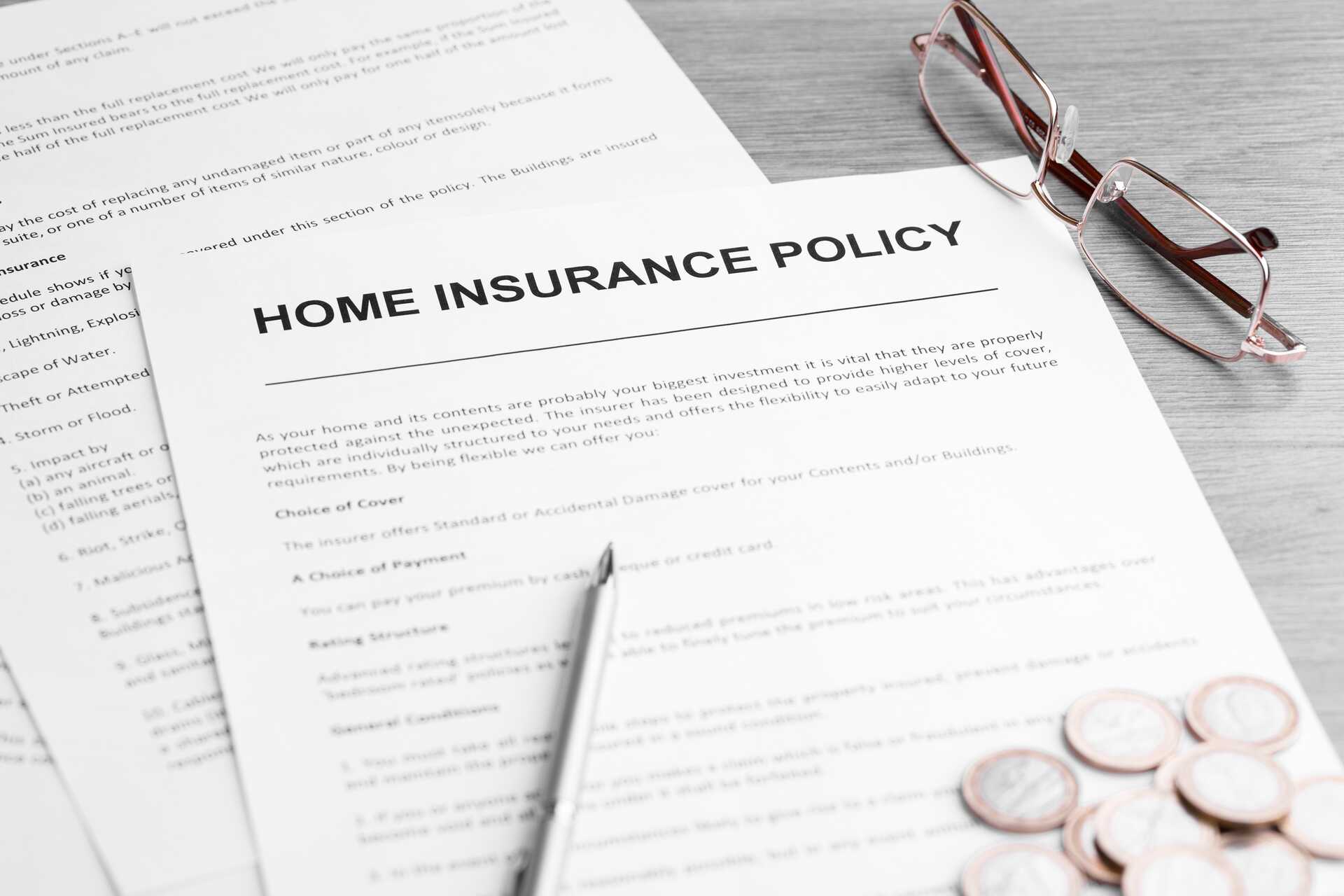 Home insurance policy document with glasses and a pen, highlighting the topic of pest control coverage and homeowner responsibilities.